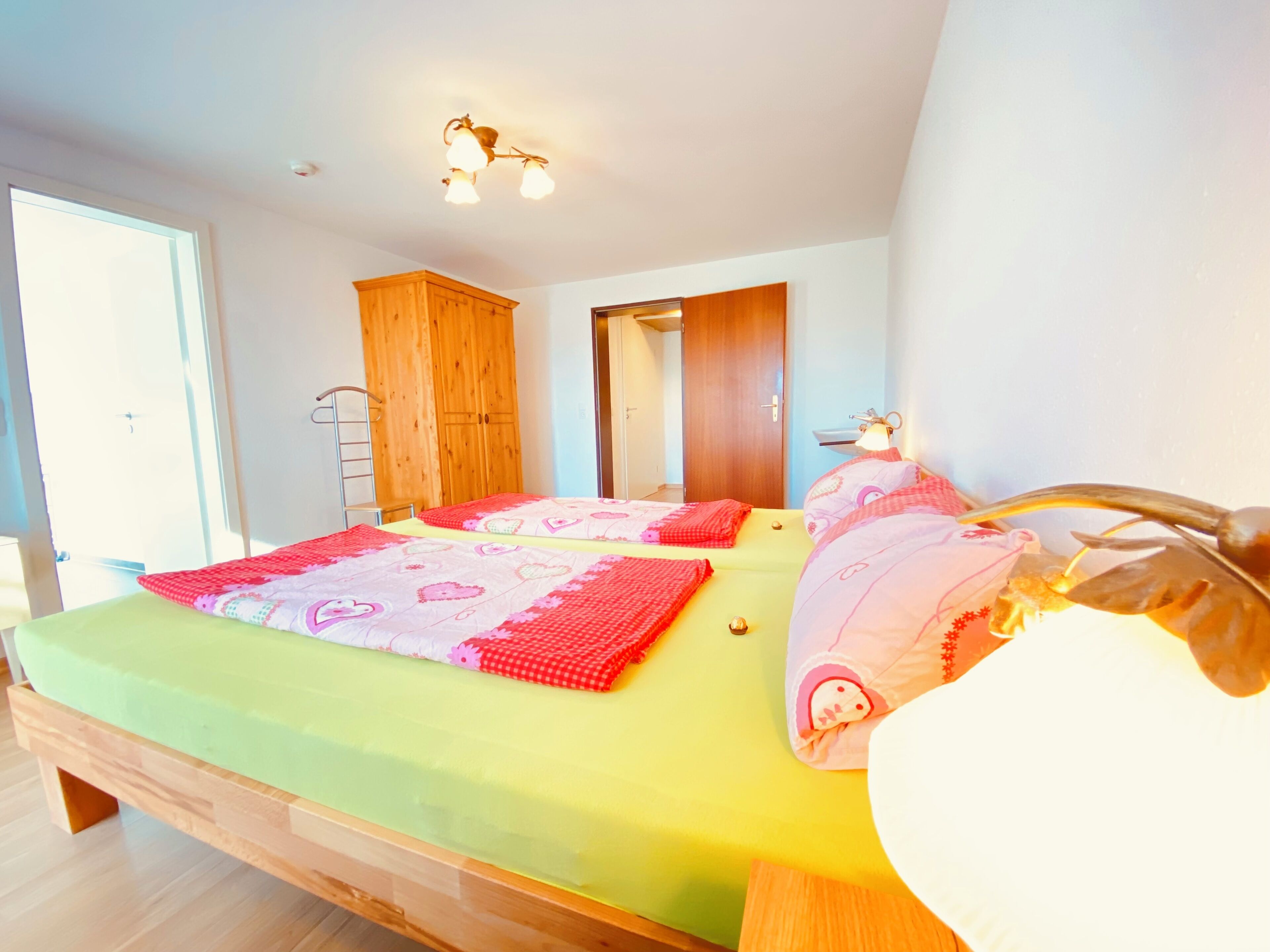 Ein Schlafzimmer mit zwei Betten, einem Holzschrank und einem Spiegel.