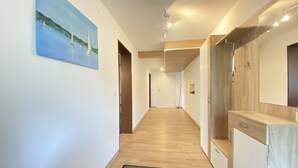 Ein moderner Flur mit Holzboden, einer schwarzen Fußmatte und einem Gemälde eines Segelbootes an der Wand.