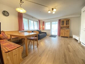 A spacious living area with a wooden dining table, a sofa, and a cabinet. - Idyllic apartment in the countryside with terrace, parking space (wallbox) and bicycle room. (Lindau (Bodensee))