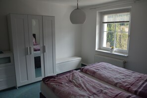 A bedroom with a bed, a wardrobe, a window with blinds, and a radiator.