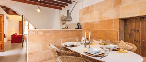 A dining area with a round table set for four, surrounded by wicker chairs.