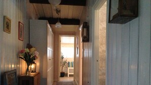 A hallway with a wooden bench, a vase with flowers, and a door leading to another room.