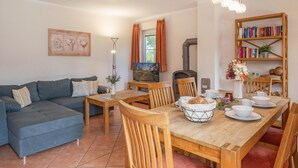 Ein gemütliches Wohnzimmer mit einer Couch, einem Esstisch mit Stühlen, einem Bücherregal und einem Kamin.