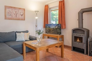 Un salon avec un canapé, une table basse, un téléviseur, une cheminée et un tableau au mur.