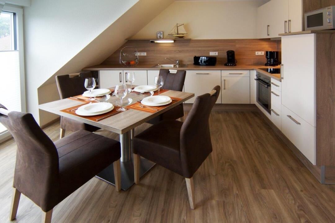 Een moderne keuken met een eethoek, voorzien van een houten tafel, stoelen en een magnetron.