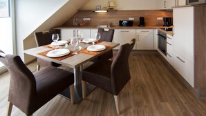Una cucina moderna con zona pranzo, che include un tavolo di legno, sedie e un forno a microonde.