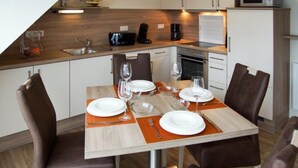 Angolo cottura compatto con tavolo da pranzo per quattro, dotato di forno a microonde, macchina del caffè e un piccolo frigorifero.