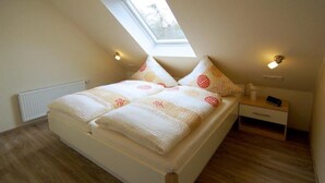 Una camera da letto con un lucernario, un letto con biancheria a motivi, un comodino con una lampada e un altro comodino.