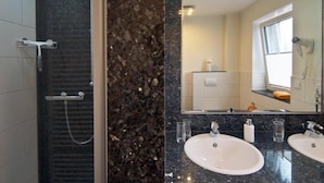 Un bagno moderno con due lavandini, uno specchio grande e una zona doccia.