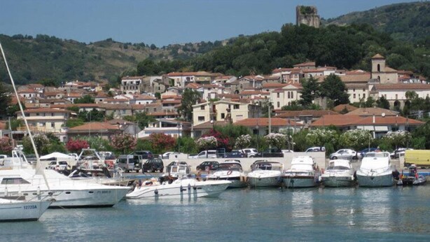 A marina with boats docked, surrounded by residential buildings with red-tiled roofs. - 'Absolutely great holiday home with a large garden near the beach' (Policastro Bussentino)