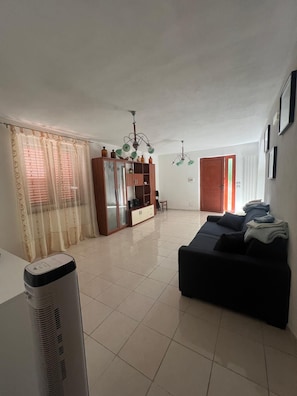 Un salon avec un canapé noir, un meuble en bois et un ventilateur de plafond.