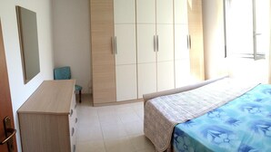A bedroom with a bed, a wardrobe, a desk, and a window. - 'Absolutely great holiday home with a large garden near the beach' (Policastro Bussentino)