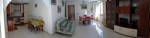 Enjoy meals in the dining area with a table set for two, accompanied by a sofa and television.