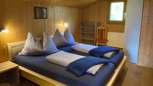 Une pièce aux murs lambrissés, avec un lit, des tables de chevet et une fenêtre.