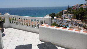 Eine Terrasse mit Meerblick, weißen Wänden und einem gefliesten Boden.