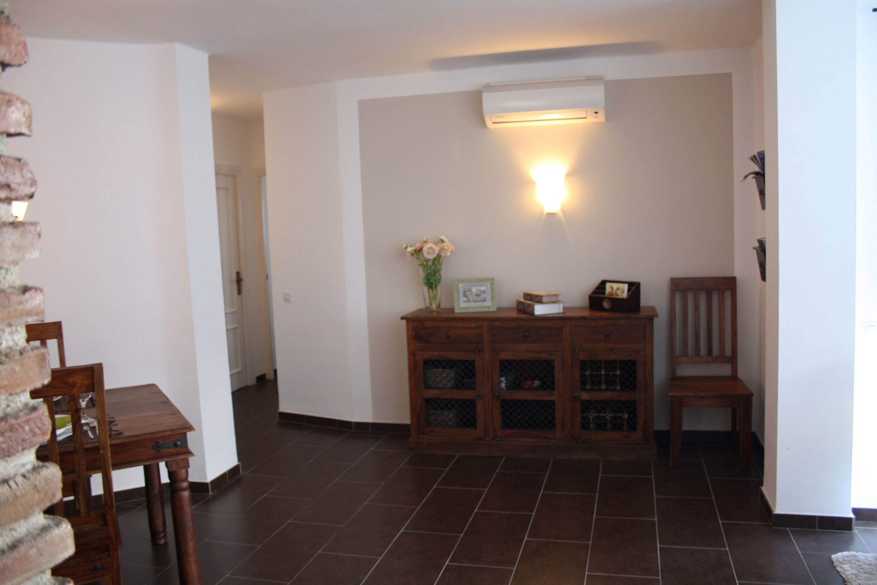 Ein Zimmer mit einem Holzkasten, einem Stuhl und einem Esstisch.