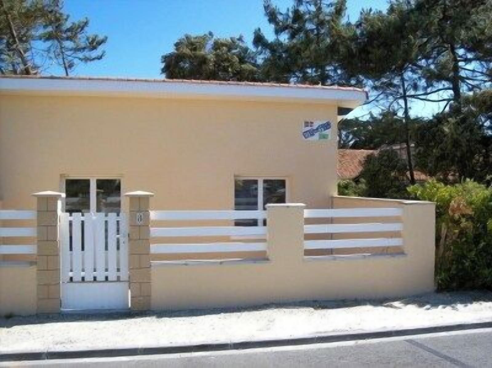 Een gebouw met een beige gevel, een hek en een klein raam.