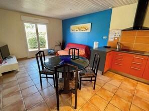 A dining area with a round table and chairs, a red sofa, and a kitchen area with red cabinets. - Gorgeous house a few steps only to the beach G0126 (Hourtin)