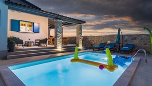 Una piscina con lettini e un muro in pietra sullo sfondo.