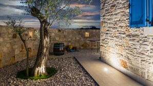 Un edificio in pietra con una porta blu, un albero nel cortile e un muro di pietra.