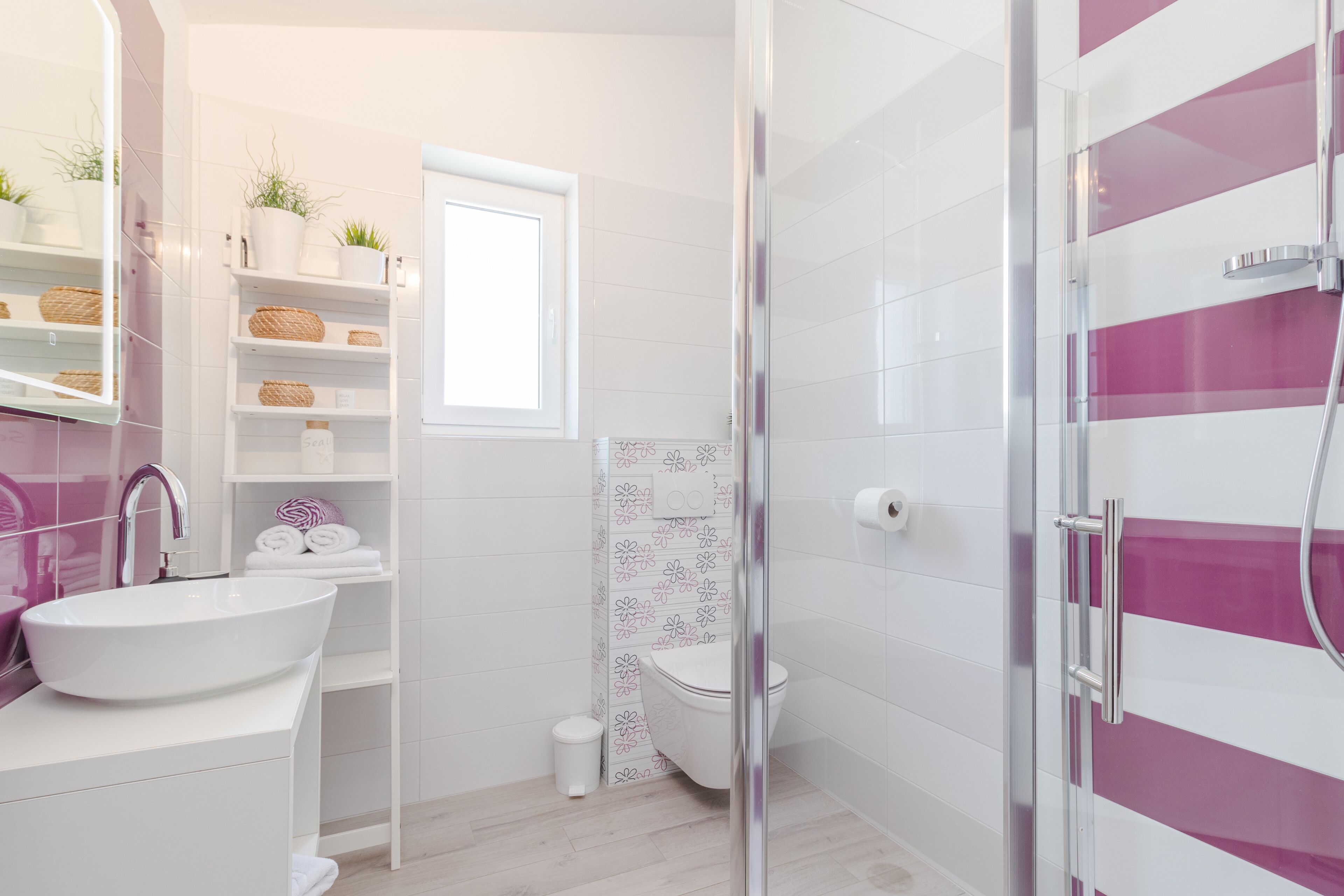 A modern bathroom with a white sink, a glass shower enclosure, and a toilet.