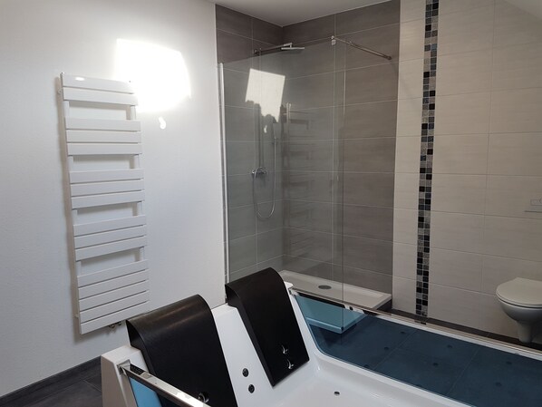 A modern bathroom with a glass-enclosed shower, a white bathtub, and a toilet. - Wellness holiday with dog, heated outdoor whirlpool, sauna, whirlpool tub, WiFi (Kobscheid Roth bei Prüm)