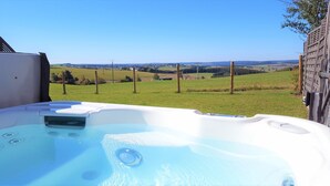 A hot tub with a clear view of a rural landscape in the background.