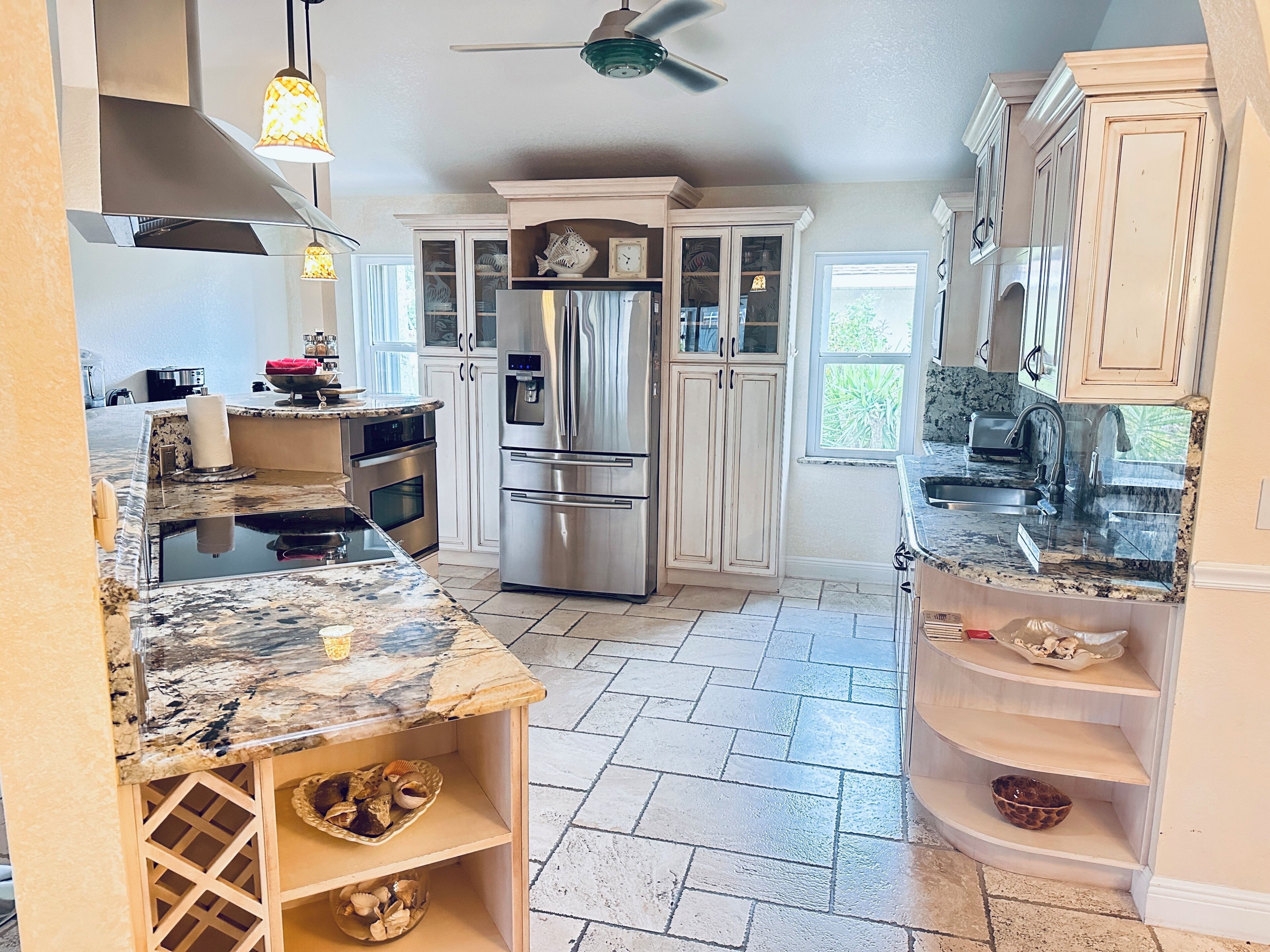 A kitchen with granite countertops, stainless steel appliances, and white cabinetry.