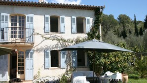 Une maison avec un balcon, un espace extérieur aménagé et couvert, et un jardin.