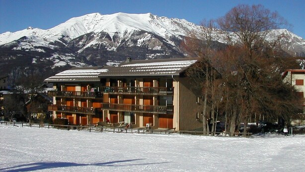Een hotel met meerdere balkons en uitzicht op besneeuwde bergen.