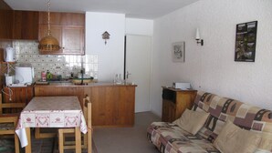 Een gezellige woonkamer met een houten bank en een eettafel met tafelkleed.
