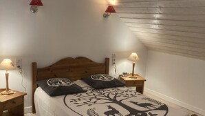 Un dormitorio con una cama de madera, dos mesitas de noche con lámparas y un techo inclinado.