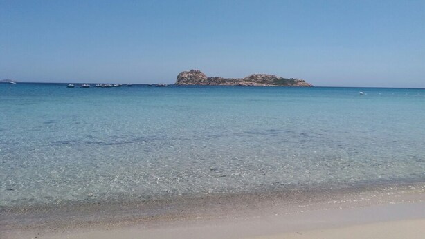 A beach with clear shallow waters and a rocky island in the distance. - Large modern hotel in the suburbs. Terrace, WiFi, conservatory low (Gonnesa)