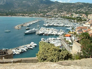 A marina with numerous boats docked, surrounded by buildings and greenery. - Apartment with terrace, seen splendid on the golf of calvi (LUMIO)