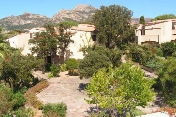 A villa with a paved courtyard surrounded by lush greenery and a mountain backdrop. - Apartment with terrace, seen splendid on the golf of calvi (LUMIO)