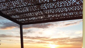 Eine Dachterrasse mit Sitzgelegenheiten im Freien, Blick auf den Sonnenuntergang und ein weiter See.