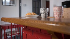 Een eettafel met een bord gebakjes, twee decoratieve kopjes en een rode stoel in een moderne keuken.