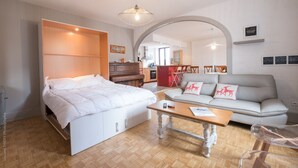 Een moderne slaapkamer met een bed, een bank, een salontafel en een eethoek op de achtergrond.
