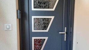 A dark blue door with three geometric glass panels, a silver handle, and a doormat with "WELCOME" engraved. - Rent cosy apartment in the heart of Lioran resort close to the slopes (Laveissière)