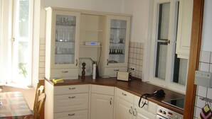 A kitchen with white cabinets, a wooden countertop, a built-in oven, and a window with a view.