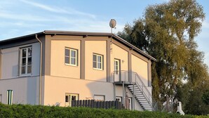 A two-story building with a flat roof, a satellite dish, and a staircase leading to the upper floor. - Idyllic natural oasis - pure tranquillity just 5 minutes' walk from the Müritz  (Ludorf)