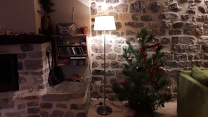 A stone wall, a Christmas tree, and a lamp in a room. - Cozy cottage in the village of 4 Tours (Valvignères)