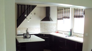 Una cocina moderna con una paleta de colores blanco y negro, estufa integrada y una ventana con cortinas a cuadros.