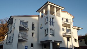 Un edificio de varios pisos con balcones, una decoración azul y blanca, y una señalización de estacionamiento visible.