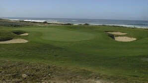 A golf course with bunkers and a view of the ocean.