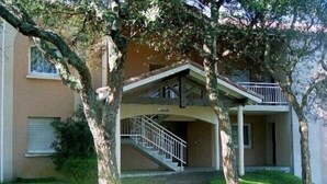 A two-story building with a covered entrance and a staircase leading to the upper floor.
