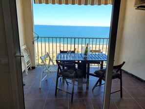 A balcony with a table, chairs, and a view of the beach.
