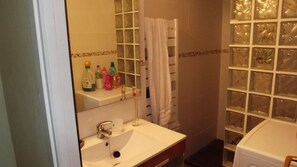 A bathroom with a sink, mirror, and shower area.
