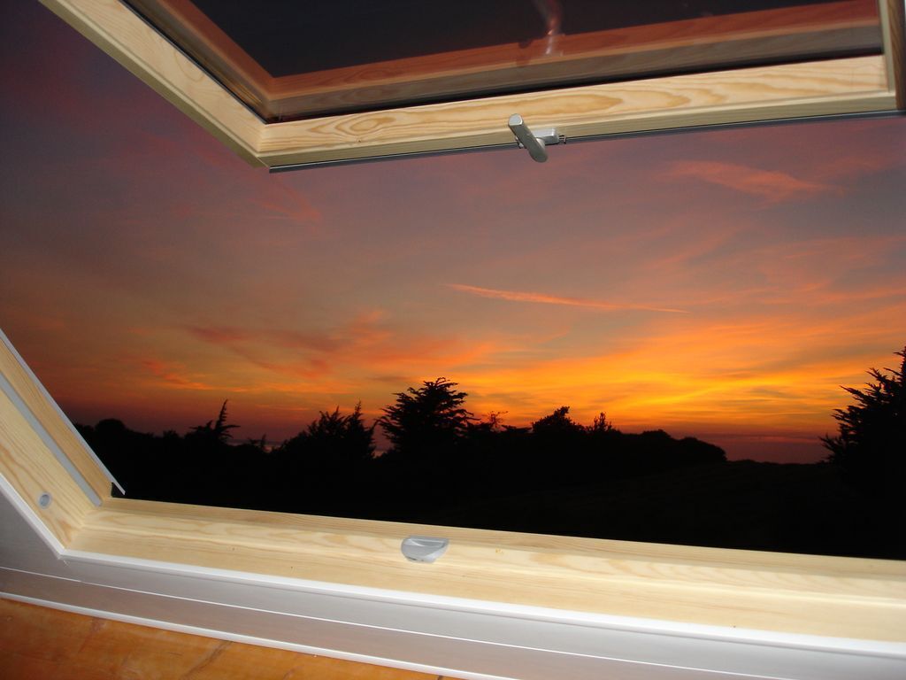 Ein Oberlicht mit Sonnenuntergangblick, ein Fensterrahmen aus Holz und ein kleiner Fensterriegel.