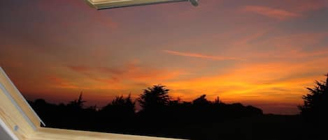 Claraboia com vista para o pôr do sol, moldura de janela de madeira e uma pequena trava.